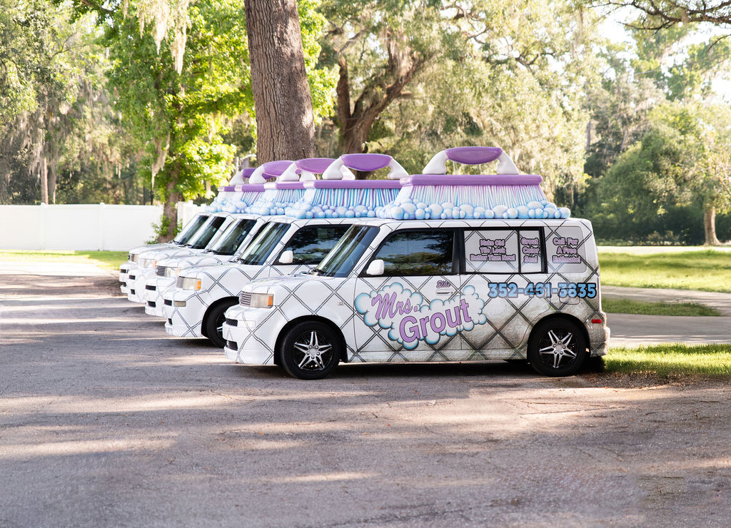 A row of Mrs. Grout service vans parked side by side outdoors, ready for scheduled customer appointments. The image highlights the company's fleet of branded vehicles serving the local community.
