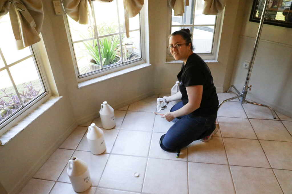Mrs. Grout team member kneeling on a tiled floor while preparing materials for a grout restoration project inside a home. The image highlights the careful preparation involved in professional tile and grout restoration.