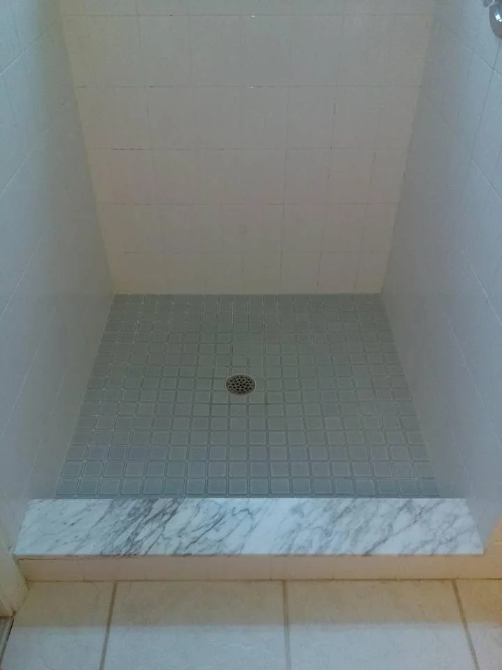 Accessible roll-in shower with a barrier-free entrance, tiled walls and floor, and a center drain. The open design supports wheelchair access and inclusive use in an accessible restroom or changing facility.
